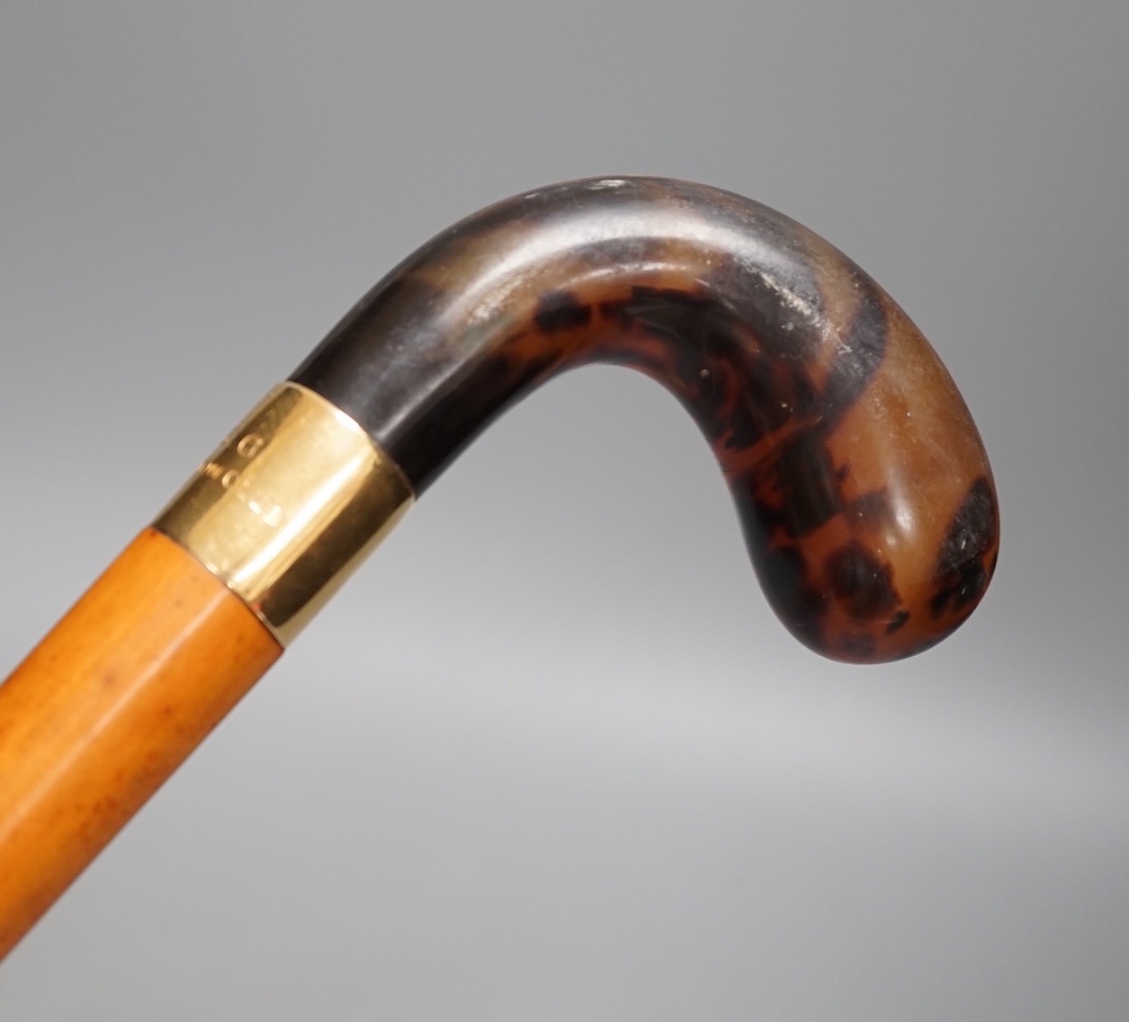 An 18ct gold collared malacca cane, with a horn handled handle, stained as tortoiseshell, 94 cms long